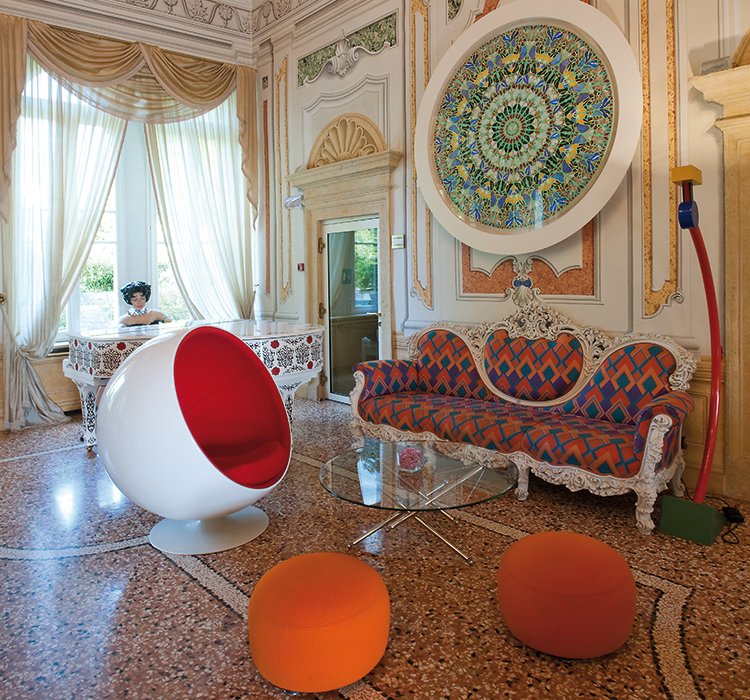 Detail of the lounge with Ball Chair, baroque sofa and large round colorful artwork