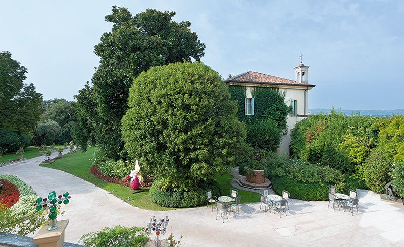 Villa garden with outdoor tables, glass sculptures and view over the Veronese countryside