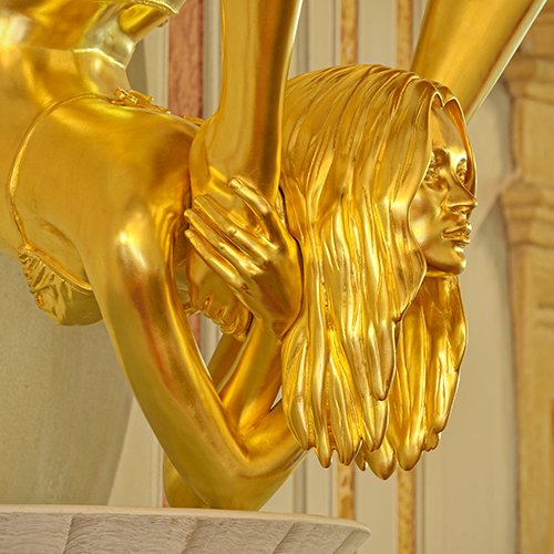 Scultura dorata con figure intrecciate di Vanessa Beecroft, esposta nell'hall del Byblos Art Hotel.