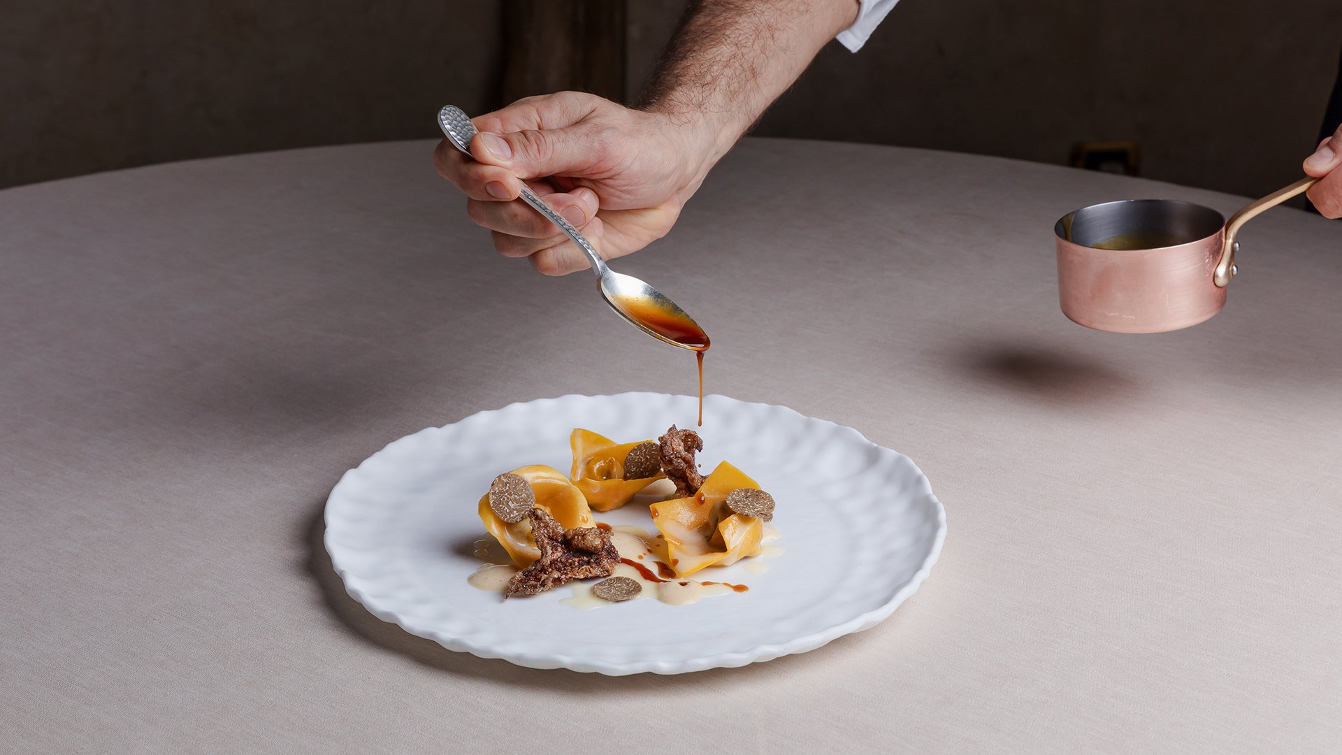 Gourmet dish at Restaurant Amistà with stuffed pasta, truffle, and sauce freshly poured