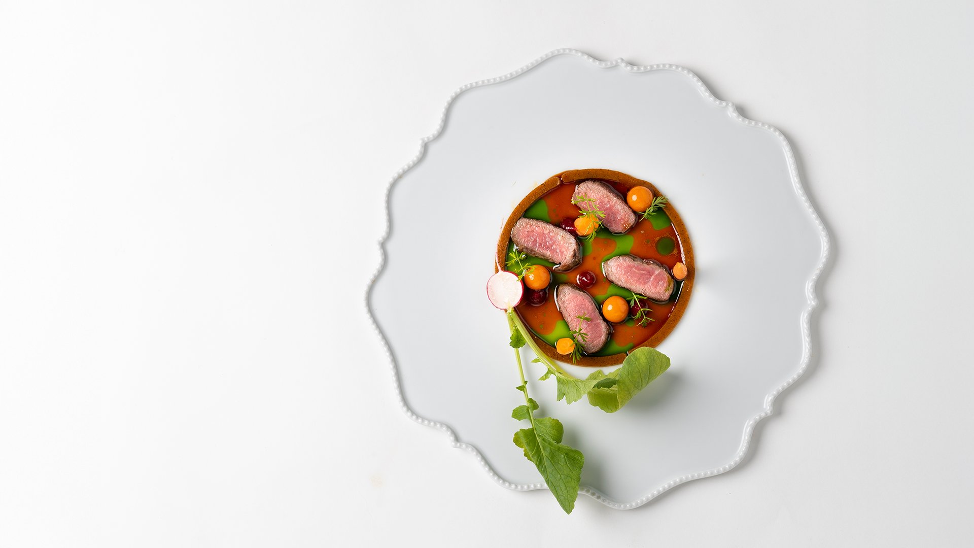 Creative dish with seared meat, vegetables, and reduction at Restaurant Amistà
