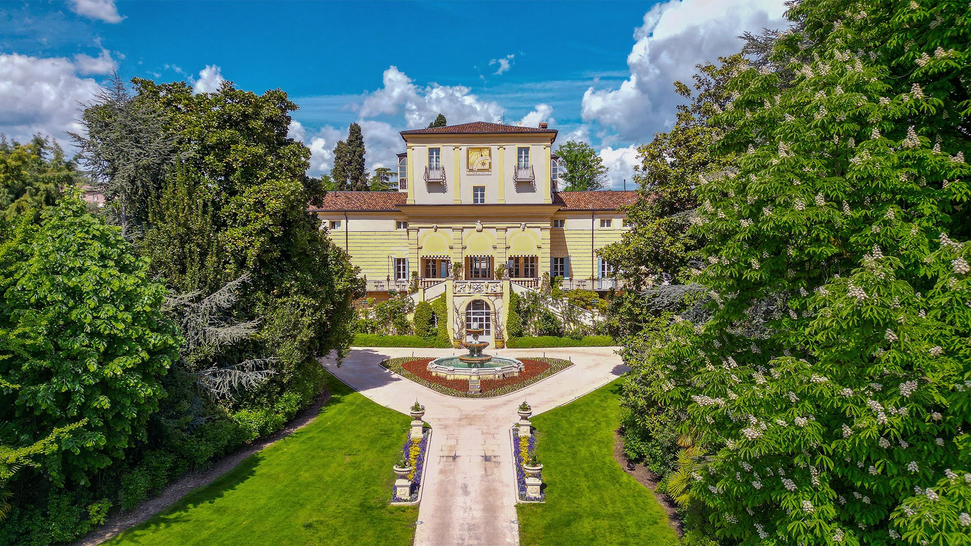 Panoramic view of the main façade of Byblos Art Hotel Villa Amistà with garden and central fountain