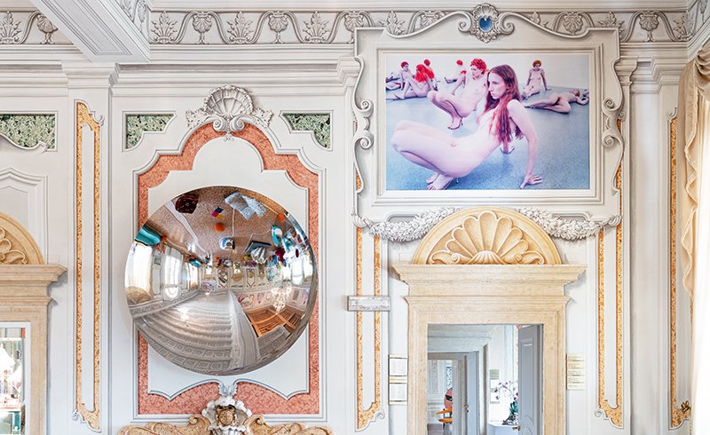 Dettaglio di parete decorata con opera fotografica di Vanessa Beecroft e specchio convesso artistico
