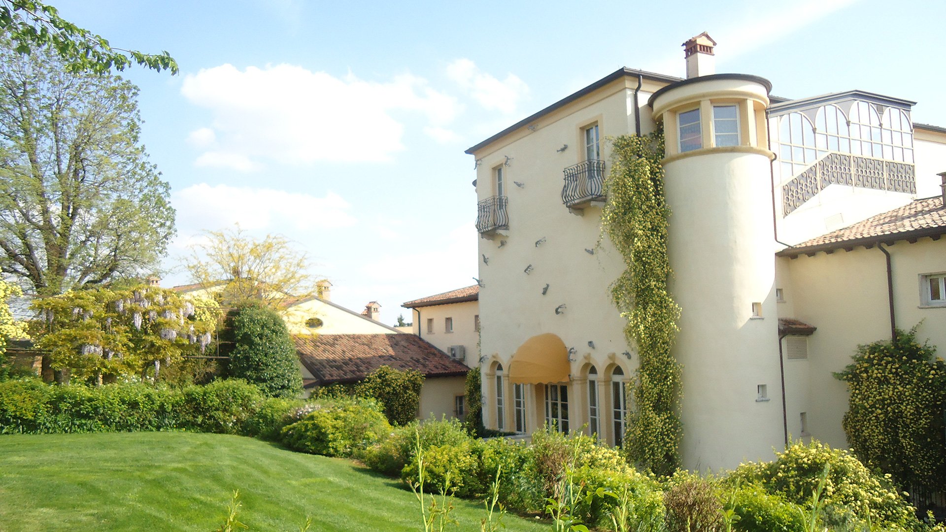 Vista laterale della villa con giardino fiorito e dettagli architettonici originali