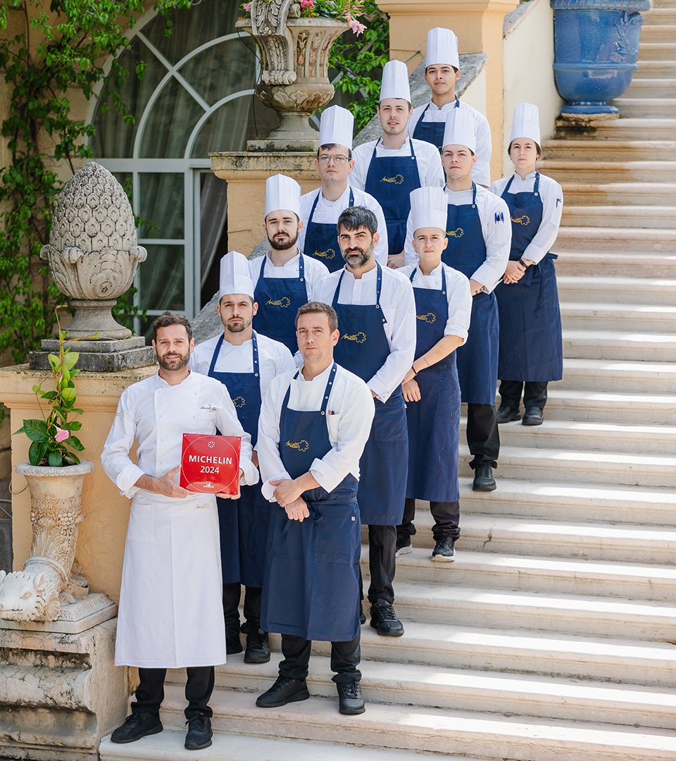 Das Küchenteam des Restaurants im Byblos Art Hotel posiert mit der Michelin-Plakette 2024 auf der Außentreppe