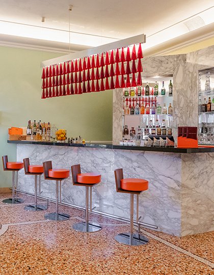 The marble counter with orange stools and bottles on display at Peter’s Bar
