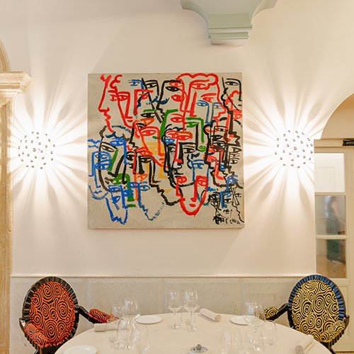 Sala elegante del ristorante Amistà con tavoli rotondi, sedie di design e opere d’arte contemporanea