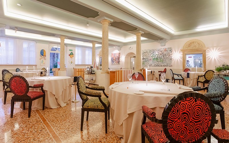 Vista ampia della sala Amistà con colonne in pietra, sedute colorate e atmosfera luminosa