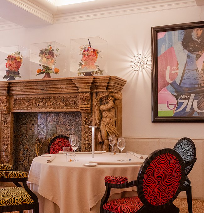 Intimate corner of Ristorante Saor with carved fireplace and contemporary artworks