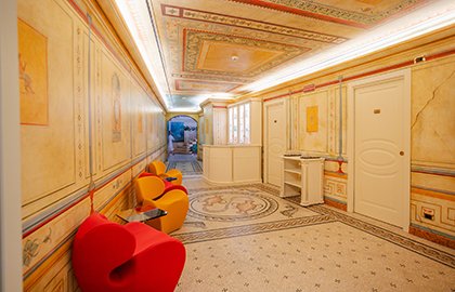 Decorated corridor leading to the wellness area, with designer seating and frescoed walls