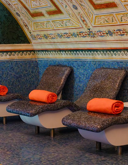 Ergonomic mosaic-covered loungers with orange towels in the relaxation area